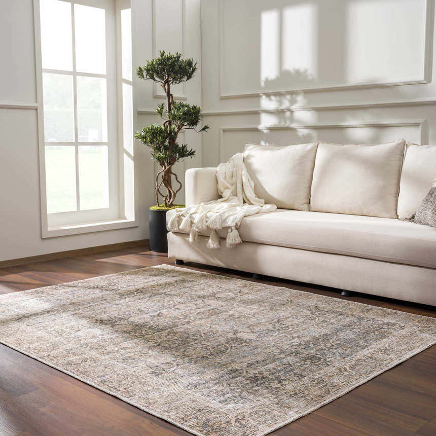 Living room scene with a beige sofa and the Ohoud Washable Area Rug in a traditional pattern on a dark wood floor. Roomscene-Rectangle