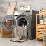Farmhouse laundry room with gray walls, wood accents, and Ohoud Washable Area Rug partially inside the washing machine. Washing-Machine