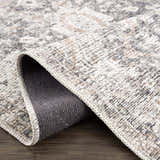 Close-up of the Mohan Washable Area Rug showing its traditional gray, beige, and white pattern and machine-woven texture. Fold