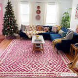 Living room with a blue sectional sofa and the Westhill Area Carpet in fuchsia and beige. Christmas tree by a pink door. Roomscene-Rectangle