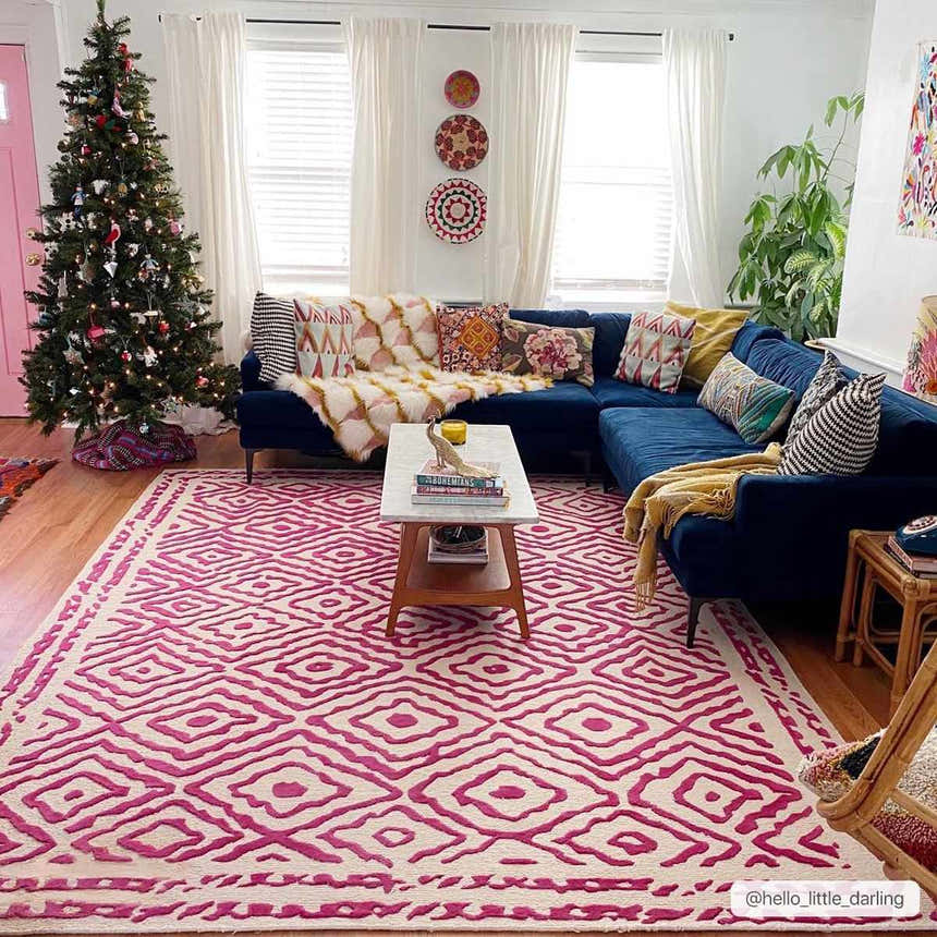 Living room with a blue sectional sofa and the Westhill Area Carpet in fuchsia and beige. Christmas tree by a pink door. Roomscene-Rectangle