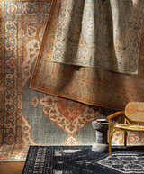 Stacked Minapan Premium Area Rugs in black, cream, and blue, with traditional oriental patterns and a woven chair. Styleshot