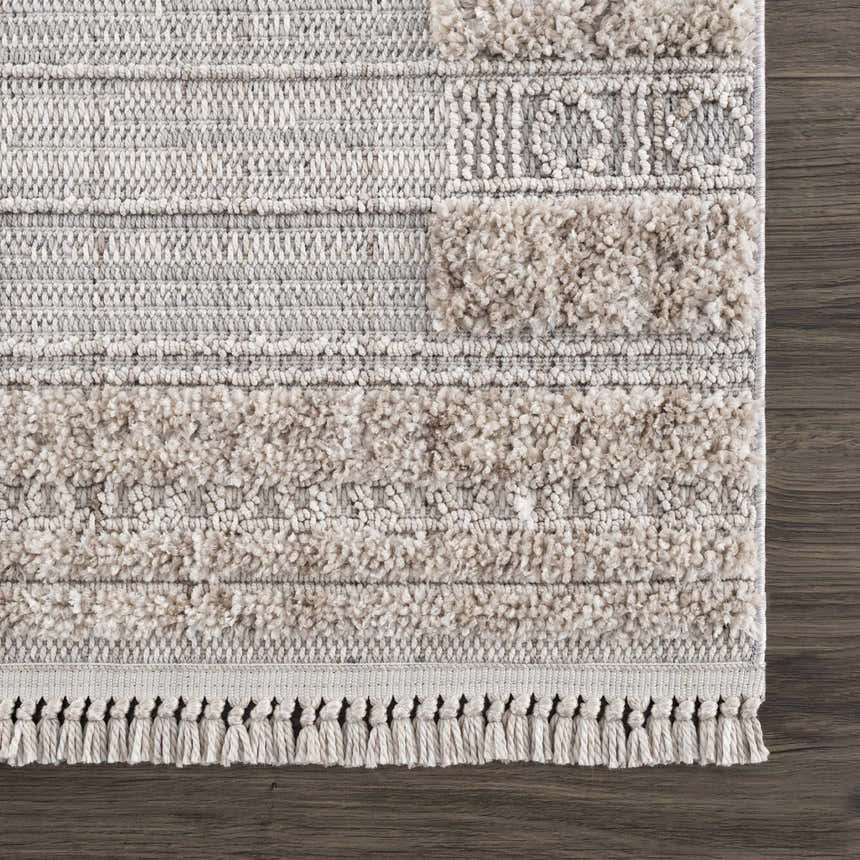 Close up of Sulak Cream Area Rug showing textured, geometric design in cream, beige, and gray on dark wood floor. Swatch