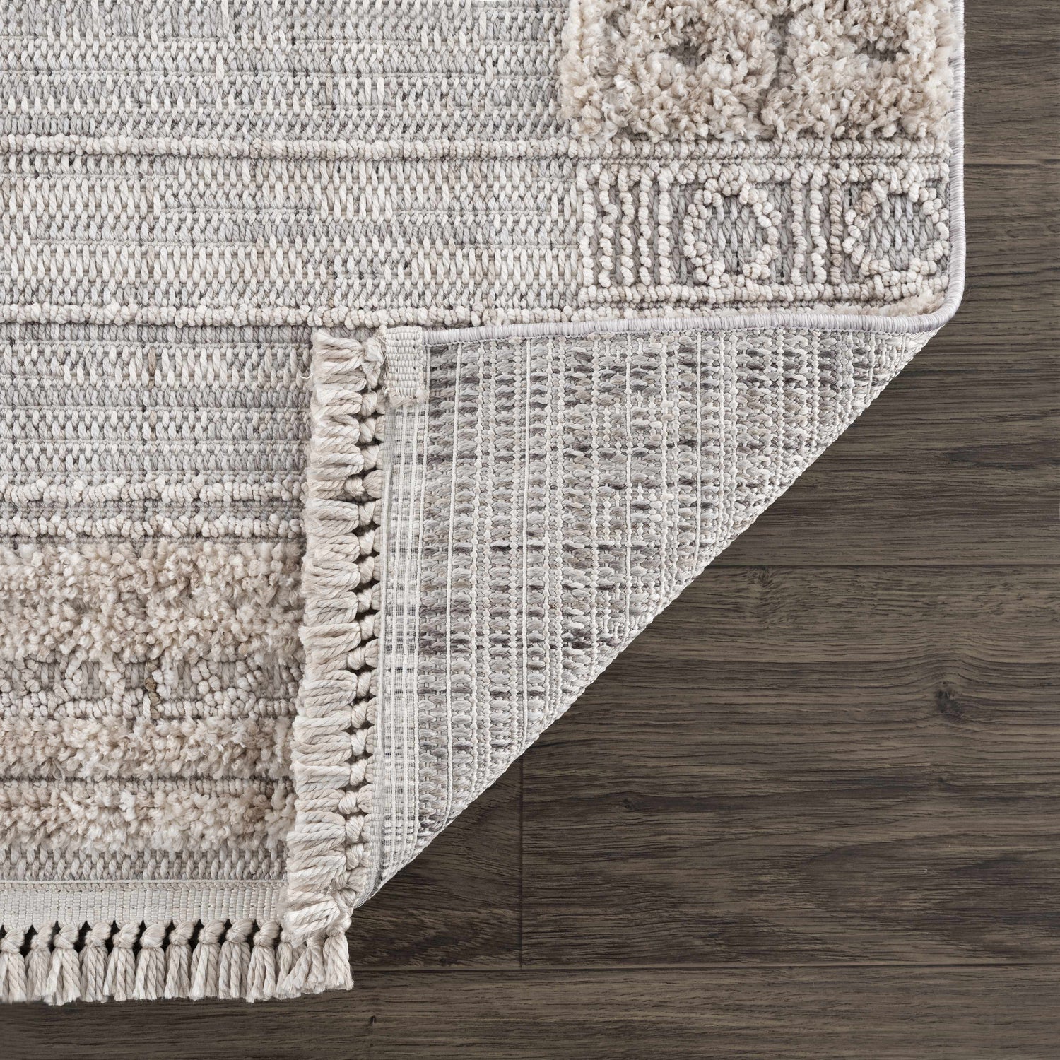 Close-up of the Sulak Cream Area Rug showing its textured pile, neutral colors, and machine-woven construction. Fold