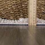 Close-up of the Sulak Cream Area Rug showing its pile height with a ruler and a woven basket in the background. Pile