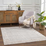Living room scene with Sulak Cream Area Rug, light gray chair, wood cabinet, and potted plant. Roomscene-Rectangle