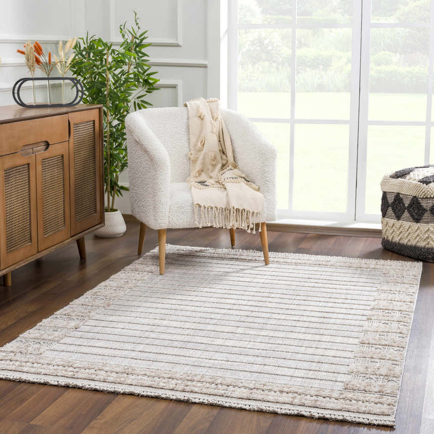 Bright living room with a Sulak Cream Area Rug, white chair, wood cabinet, and large window. Roomscene-Rectangle