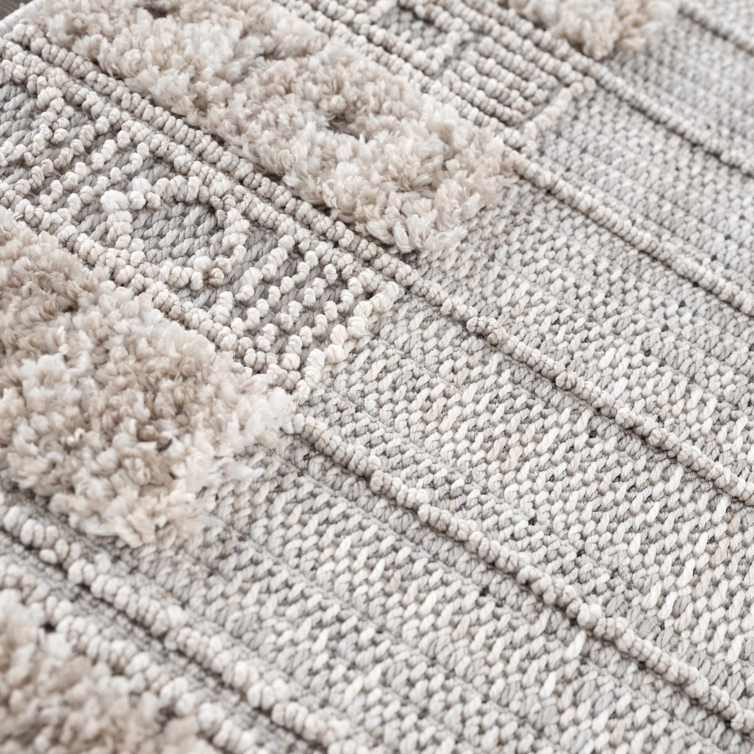 Close-up of the Sulak Cream Area Rug showing its textured weave and cream-colored tufted details. Texture
