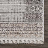 Close-up of the Naivasha Elegant High/Low Area Rug showing its charcoal, cream, and gray textured design and fringe. Swatch