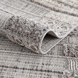 Close-up of Naivasha Elegant High/Low Area Rug. Charcoal, cream, and gray textured rug with a high-low pile design. Fold