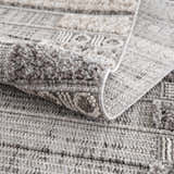 Close-up of the Naivasha Elegant High/Low Area Rug, showing its charcoal, cream, and gray textured pattern. Fold