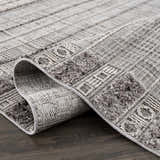 Close-up of the Naivasha Elegant High/Low Area Rug showing its charcoal, cream, and gray textured pattern. Fold