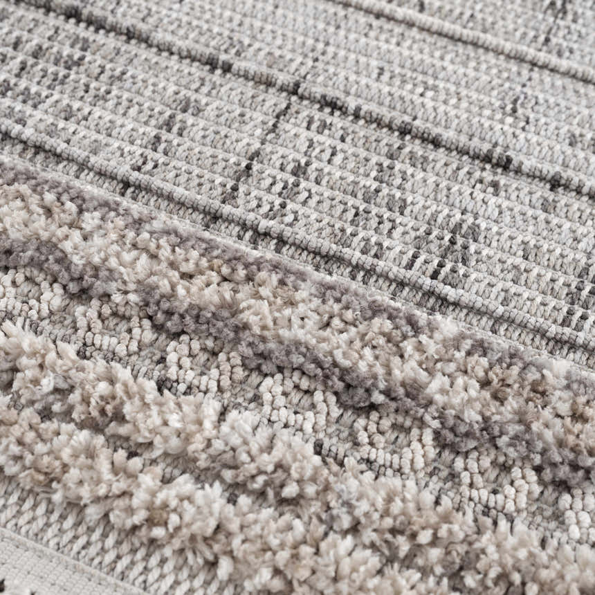 Close-up of the Naivasha Elegant High/Low Area Rug. Features charcoal, cream, and gray tones with a textured, high-low pile. Texture