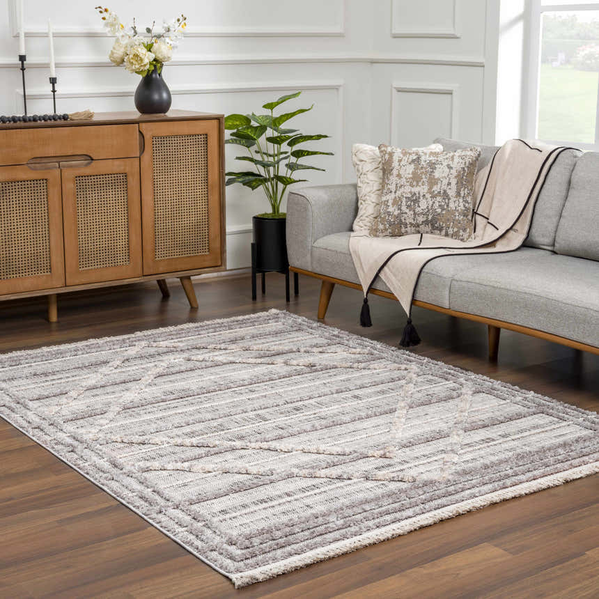 Living room scene with gray sofa and Barurao Area Rug in charcoal, cream, light beige, and gray with geometric pattern. Roomscene-Rectangle
