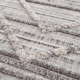Close up of Barurao Area Rug showing the charcoal, cream, and gray geometric pattern and textured, machine woven construction. Texture