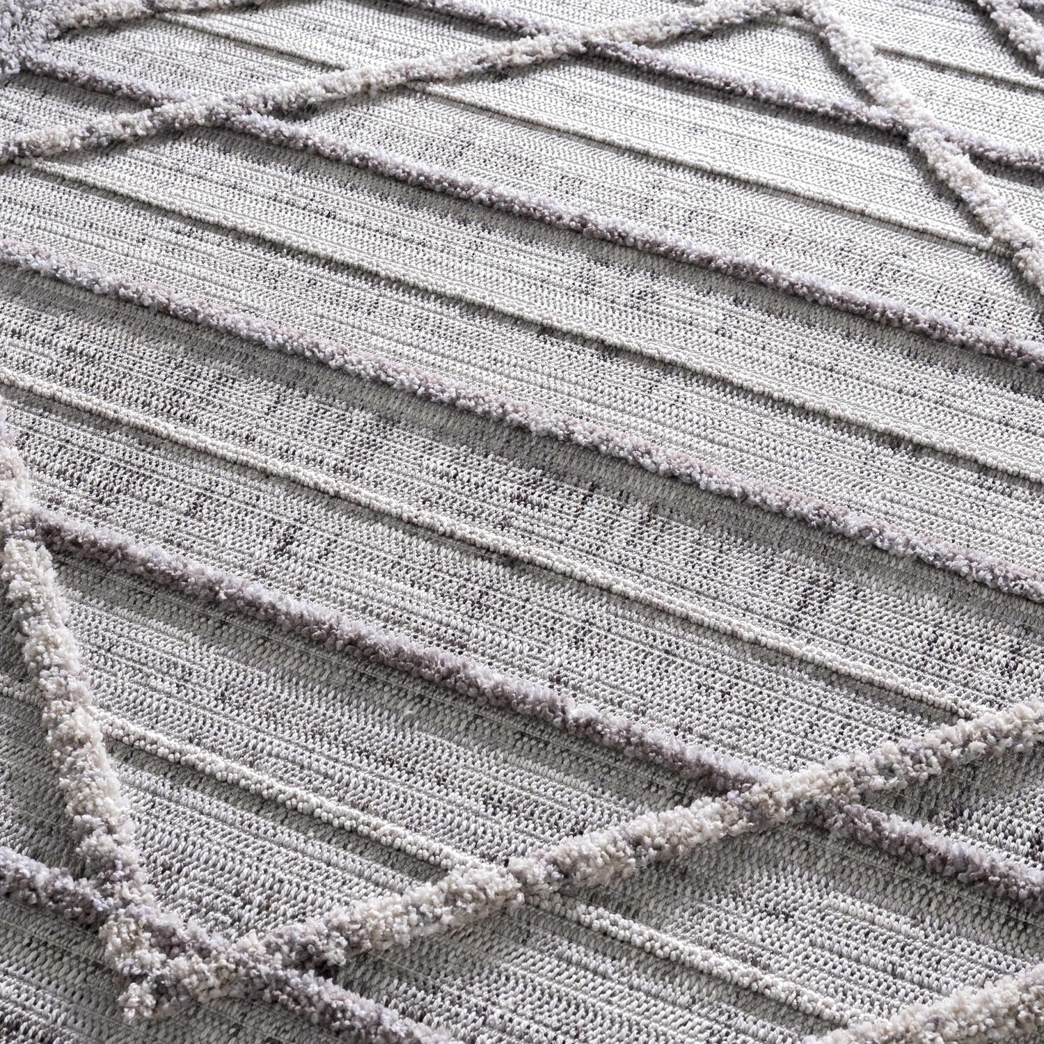 Close-up of the Barurao Area Rug, showcasing its charcoal, cream, and gray geometric pattern and textured, machine-woven construction. Texture