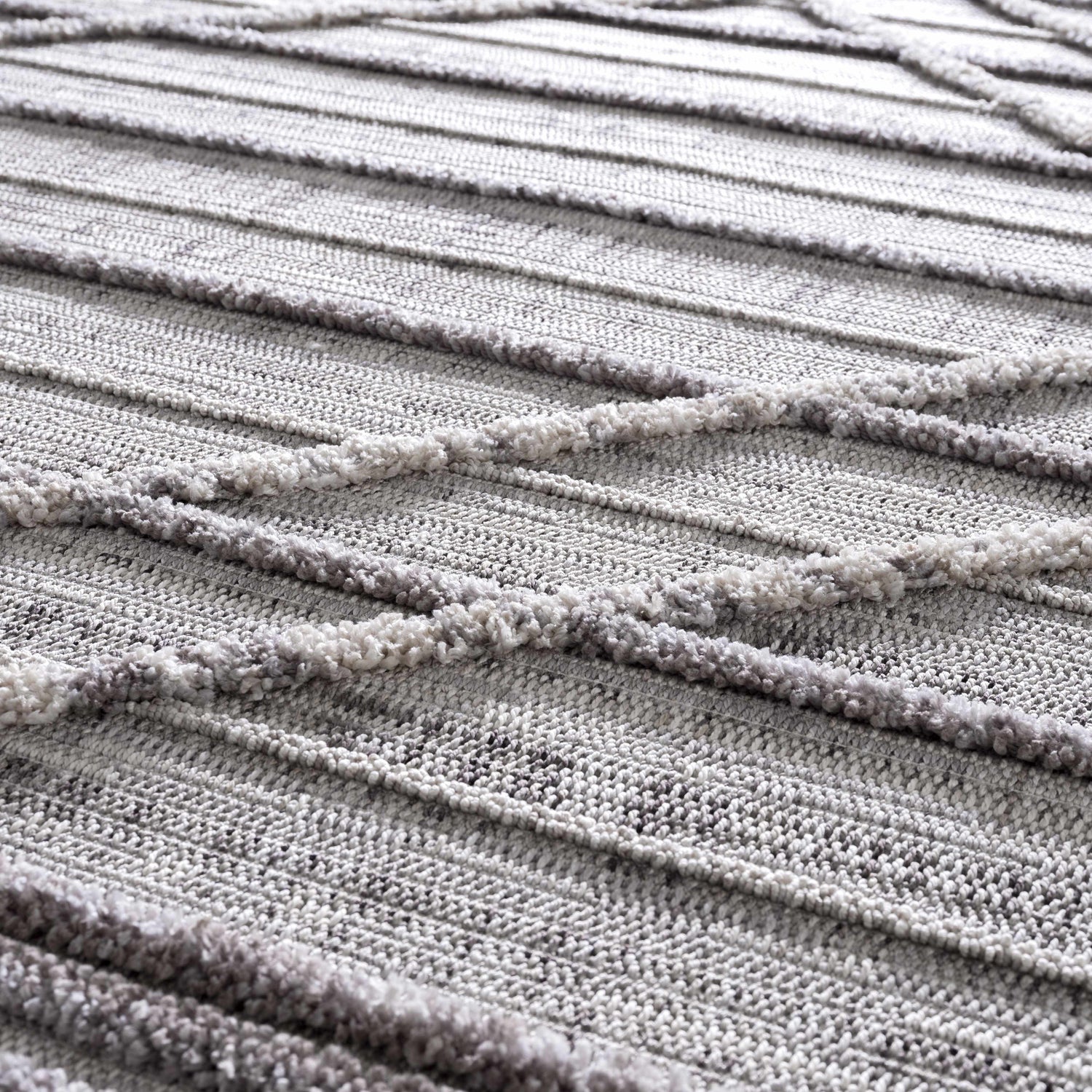 Close-up of Barurao Area Rug showing charcoal, cream, and gray geometric pattern with textured, raised stripes. Texture