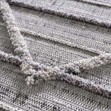 Close-up of the Barurao Area Rug showing its charcoal, cream, and gray geometric pattern and textured, plush pile. Texture