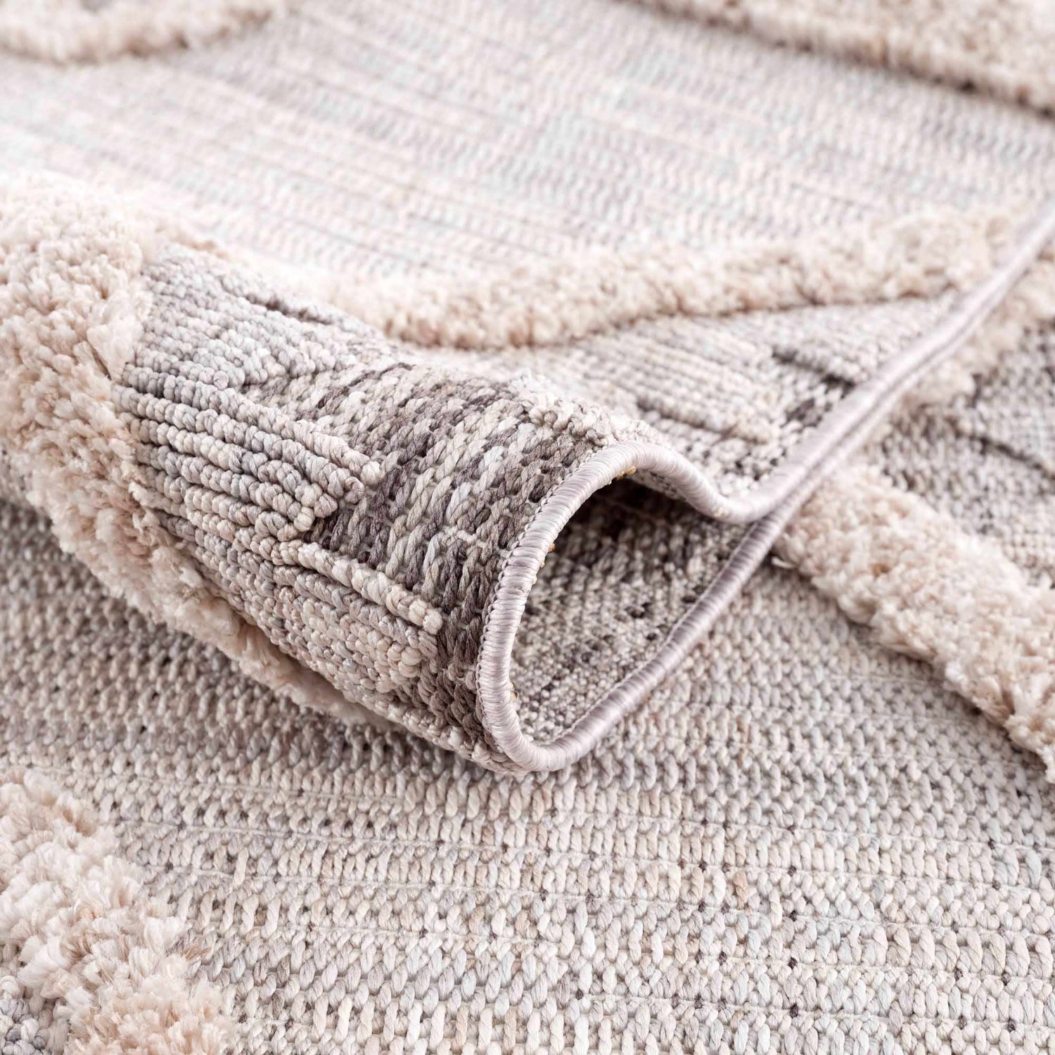 Close-up of the Serkomen High-Low Area Rug. Neutral tones, geometric pattern, and textured, high-low pile. Fold