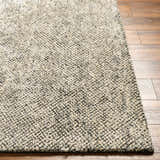 Close up of the Abiba Area Rug showing beige and black textured design on wood floor. Front