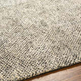 Close-up of the hand-loomed Abiba Area Rug, a contemporary design in beige, black, and taupe, with a textured wool and viscose blend. Texture