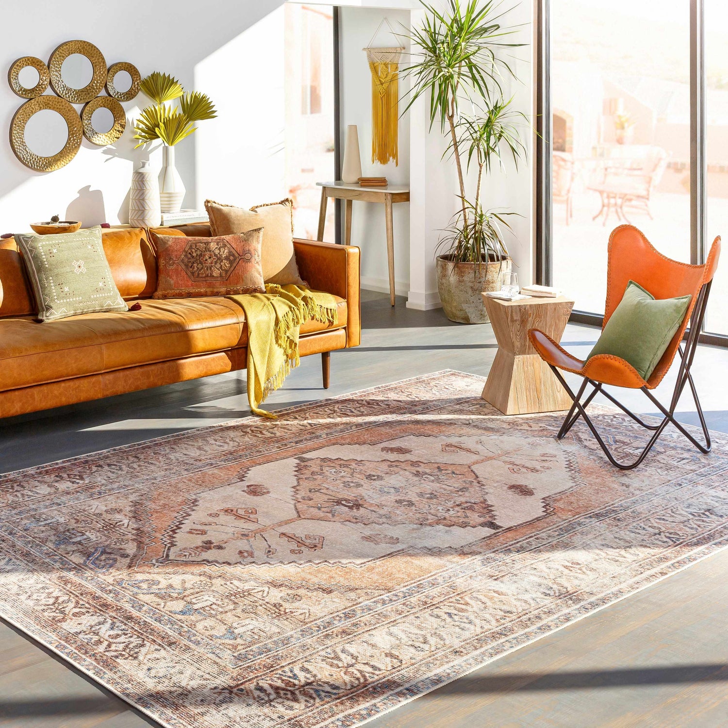 Living room scene with a brown leather sofa and Arncliffe Washable Area Rug in brown, tan, and ivory tones. Roomscene-Rectangle