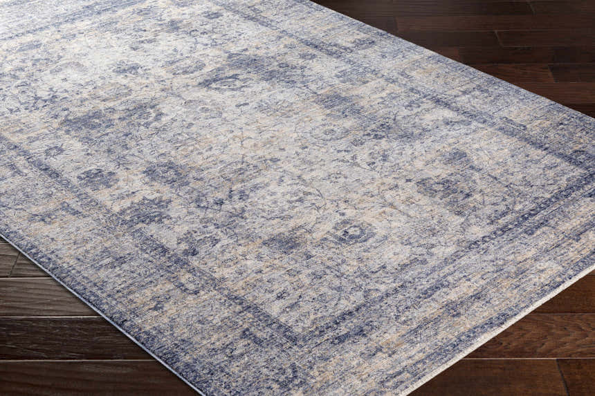 Close-up of the Accokeek Luxe Area Rug showing its denim, light beige, and navy vintage-inspired pattern and soft texture. Corner