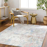 Living room scene with the Ahava Washable Area Rug. White rug with blue, pink, and tan accents. Modern chair and gold accents. Roomscene-Rectangle