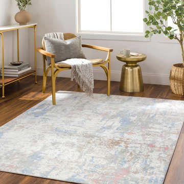 Living room scene with the Ahava Washable Area Rug. White rug with blue, pink, and tan accents. Modern chair and gold accents. Roomscene-Rectangle
