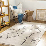 Living room scene with a contemporary AISHA Area Rug, white chair, and wooden accents. Roomscene-Rectangle