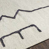 Close up of the Aisha Area Rug showing its ivory wool texture and geometric charcoal design. Texture