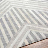 Close-up of the Akiye Area Rug, a geometric design in beige, cream, and gray leather and viscose. Fold