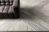 Living room scene with a gray sofa on the Akiye Area Rug, a geometric rug in beige, cream, and gray. Styleshot