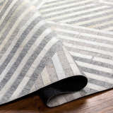 Close-up of the Akiye Area Rug showing beige, cream, and gray geometric stripes and hand-crafted texture. Fold