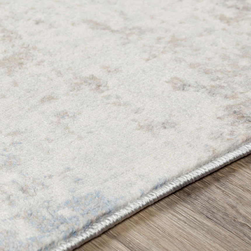 Close-up of the Alcove Abstract Area Rug showing its ivory, gray, and blue abstract pattern and soft texture. Texture