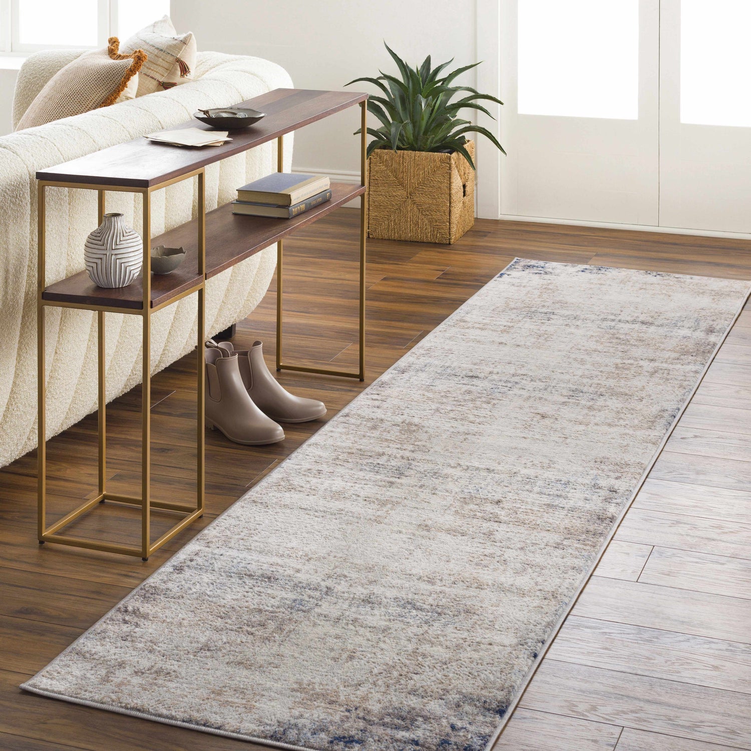 Living room scene with Alcove Abstract Area Rug runner in light gray, ivory, and blue. Styled with console table, plant, and sofa. Roomscene-Runner