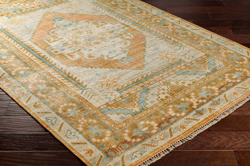 Close-up of the hand-knotted Aliang Premium Rug. Traditional design in blue, camel, and cream on dark wood floors. Corner