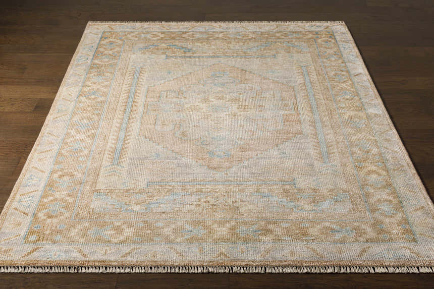 Close-up of the hand-knotted Aliang Premium Rug. Oriental design in cream, tan, and light blue on a dark wood floor. Front