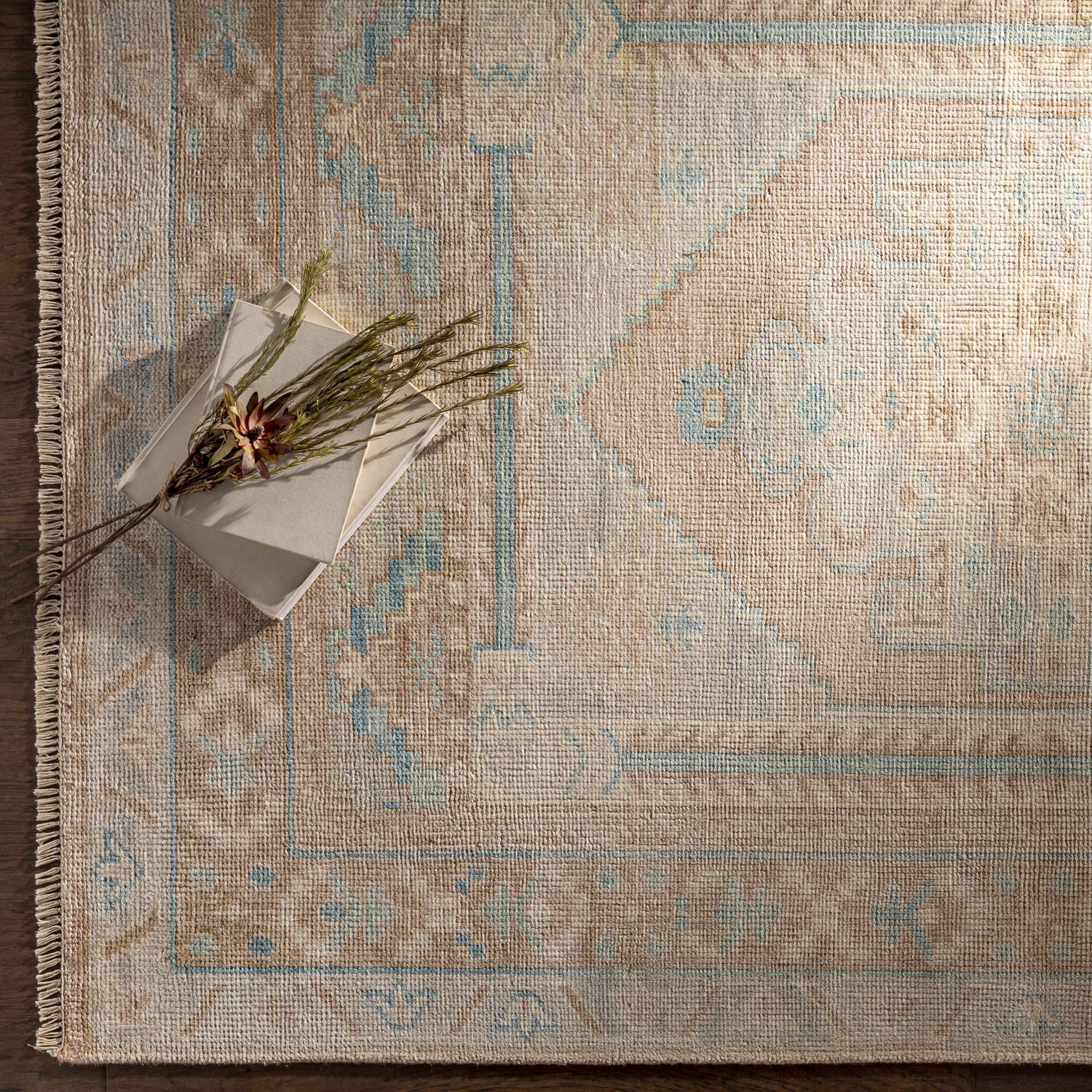Close-up of the hand-knotted Aliang Premium Rug. Features a traditional design in camel, cream, and light blue wool. Styleshot