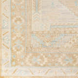 Close-up of the hand-knotted Aliang Premium Rug. Features a traditional pattern in cream, tan, and light blue hues. Wool texture. Swatch