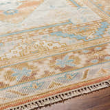 Close-up of the hand-knotted Aliang Premium Rug. Features traditional patterns in blue, camel, cream, and pink tones. Texture