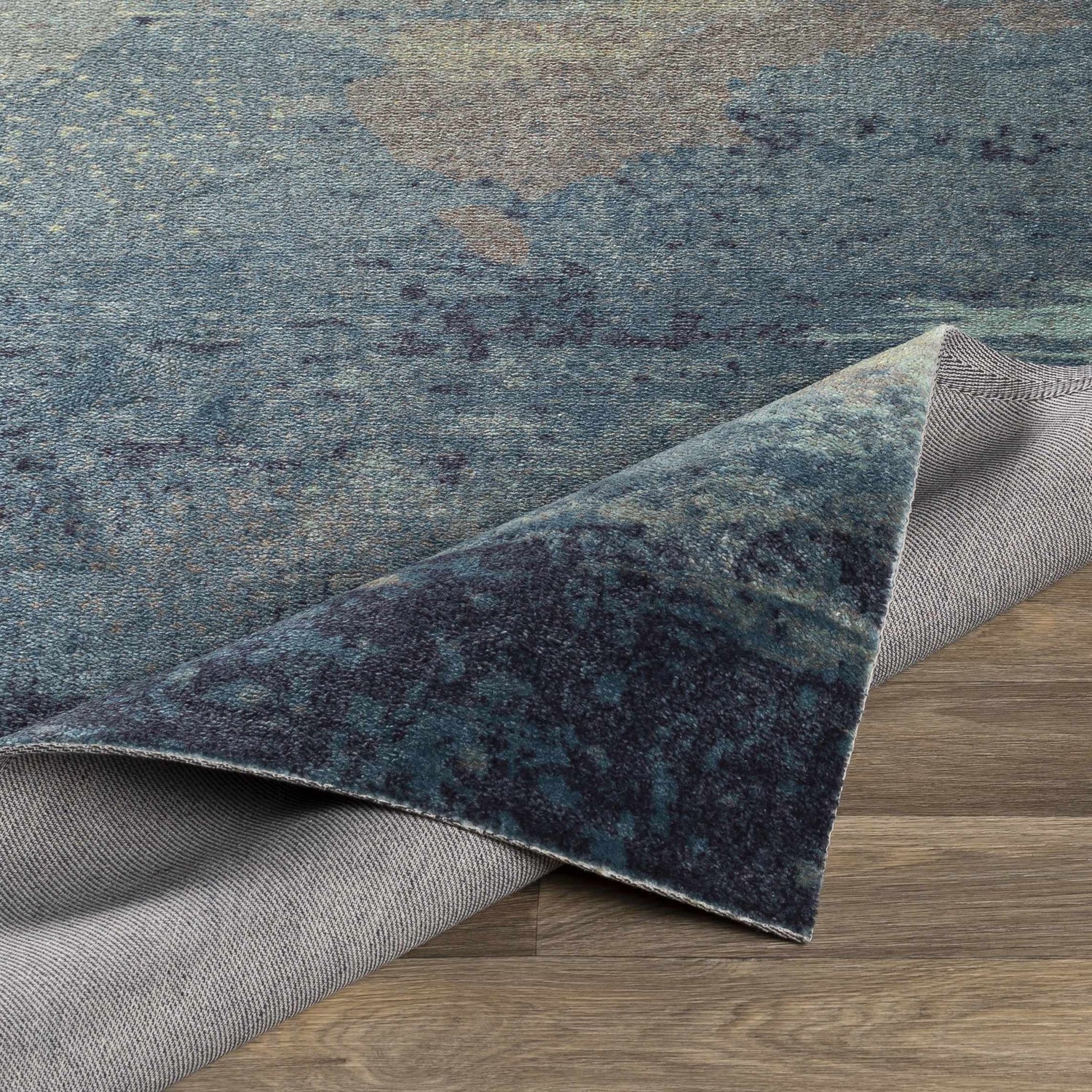 Close-up of the Alvaton Abstract Blue Rug showing its blue, gray, and denim hues and machine-woven texture. Fold
