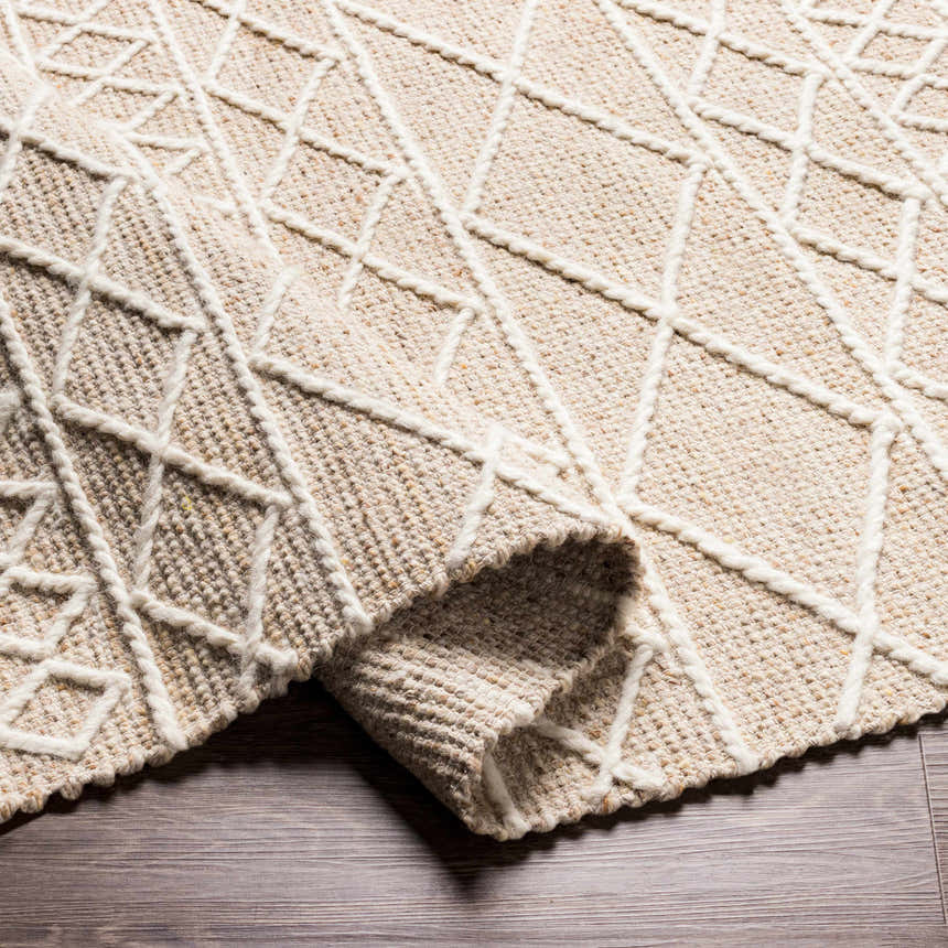 Close-up of the Ambulong Area Rug, a hand-woven rug with a cream and tan geometric pattern and medium brown wool and cotton texture. Fold