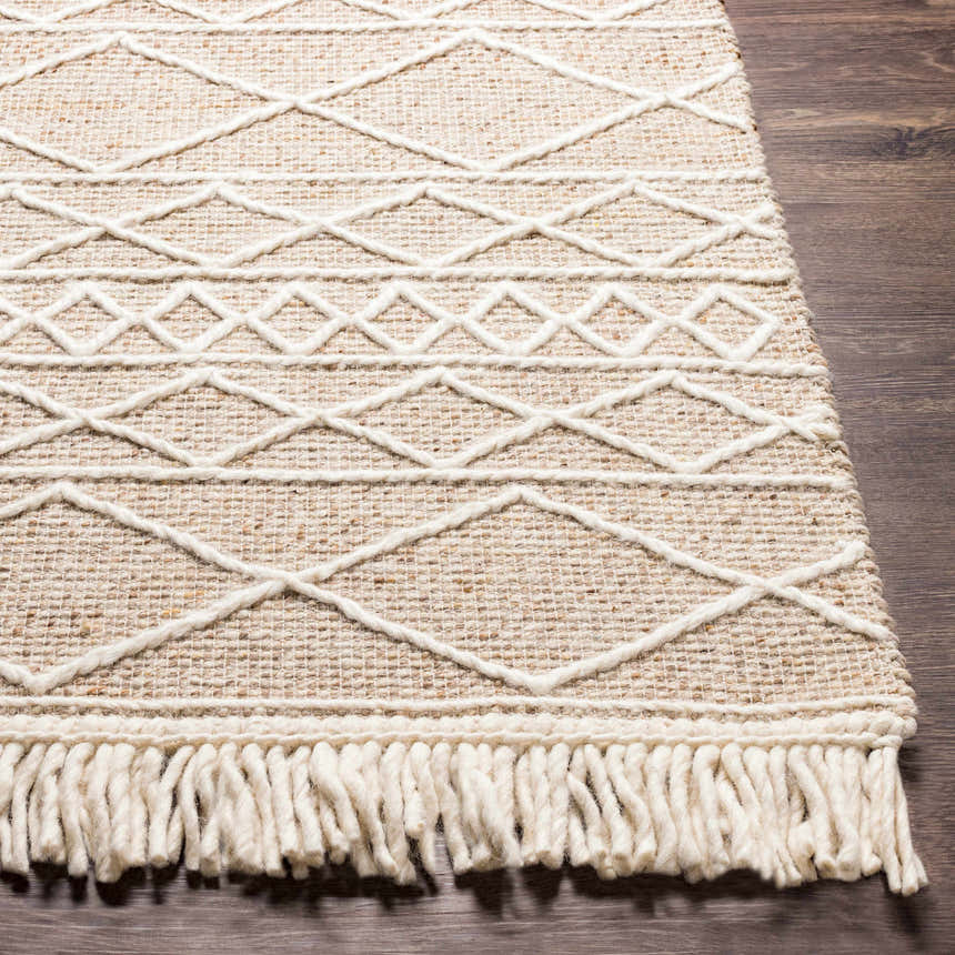 Close-up of a cream Ambulong Area Rug. Hand-woven wool and cotton rug with geometric pattern and fringe detail. Front