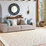 Living room scene with a tan sofa and the cream Ambulong Area Rug featuring a geometric pattern. Roomscene-Rectangle
