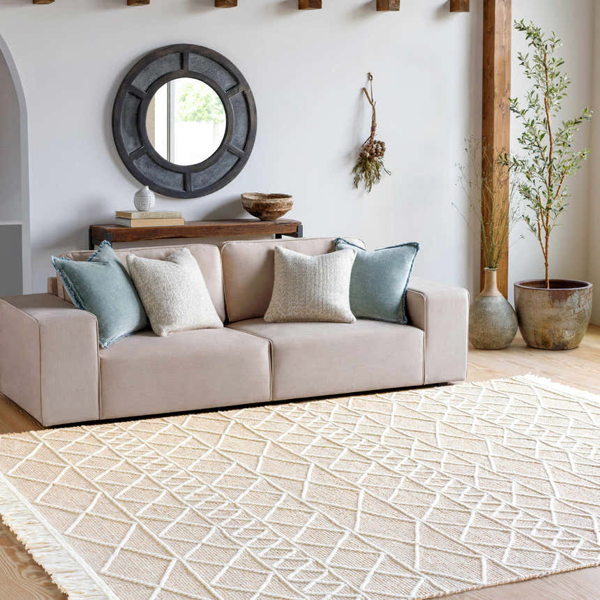 Living room scene with a tan sofa and the cream Ambulong Area Rug featuring a geometric pattern. Roomscene-Rectangle
