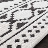 Close up of the Amoret Area Rug showing its black and off-white bohemian pattern and textured weave. Texture