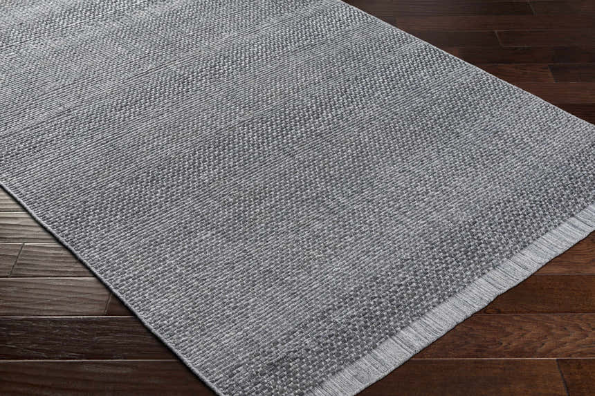 Close-up of the Yong Hand Loomed Gray Indoor & Outdoor Rug showing its woven texture and charcoal and light slate colors. Corner