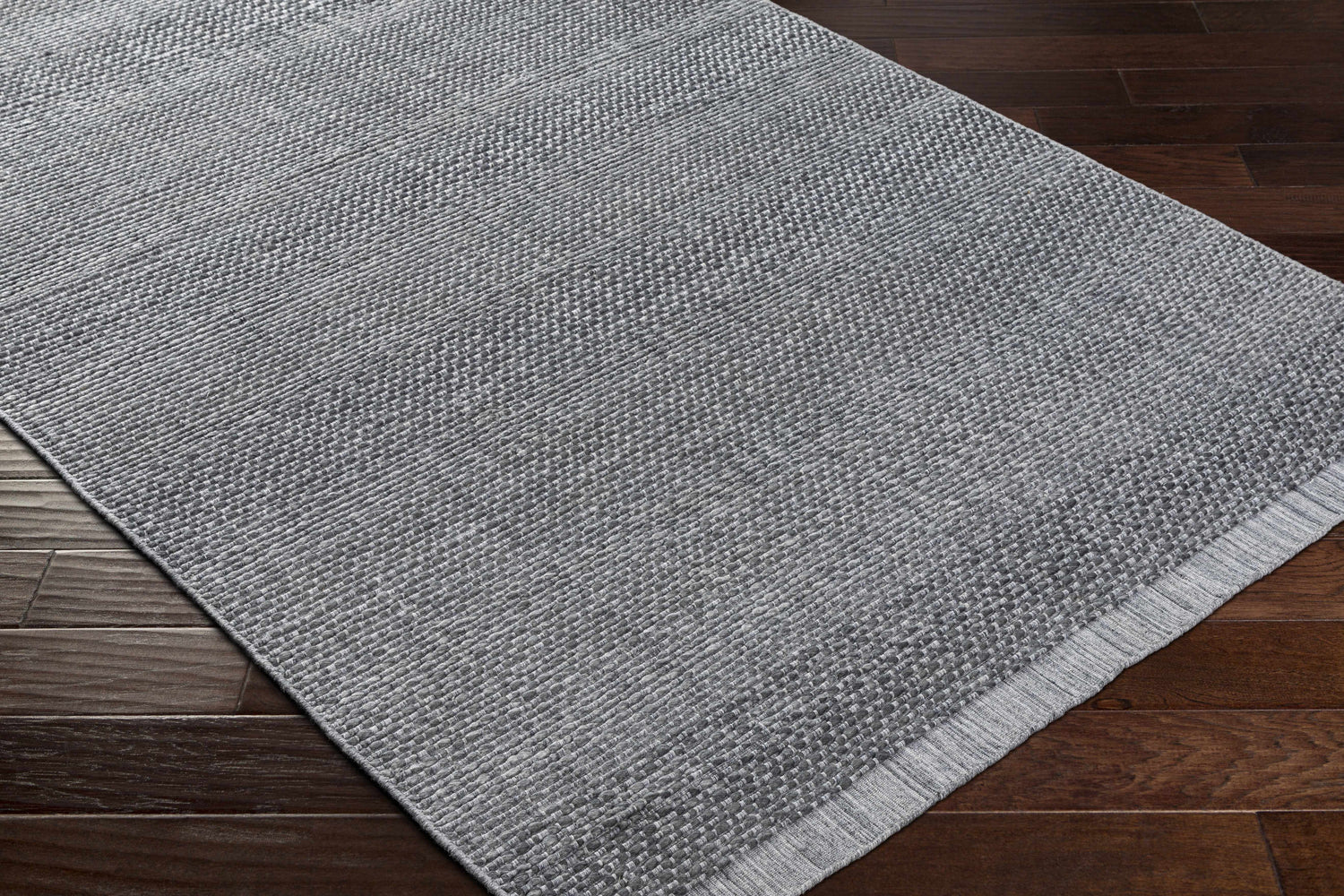 Close-up of the Yong Hand Loomed Gray Indoor & Outdoor Rug showing its woven texture and charcoal and light slate colors. Corner