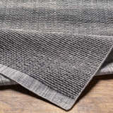Close-up of the gray Yong Hand Loomed rug showing its textured, horizontal weave and recycled PET yarn material. Fold